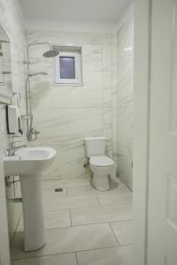 a white bathroom with a toilet and a sink at Hotel Taverna Zisi in Ersekë