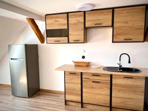 a kitchen with wooden cabinets and a stainless steel refrigerator at Noclegi przy Gołębiarce in Wleń