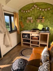 a kitchen with a stove and a couch in a room at Rhodes To Serenity - Mermaid Shepherds Hut in Stoke on Trent