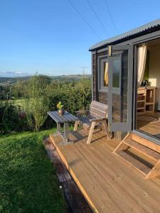 Cette cabine dispose d'une terrasse en bois avec un banc et une table. dans l'établissement Rhodes To Serenity - Mermaid Shepherds Hut, à Stoke-on-Trent