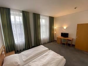 a bedroom with a bed and a desk and windows at Kolbeck Rooms in Vienna