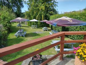 een houten hek met twee tafels en parasols bij Llanina Arms in Llanarth