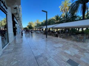 eine Straße mit Tischen, Stühlen und Palmen in der Unterkunft Hostal Ventura Premium in Alicante