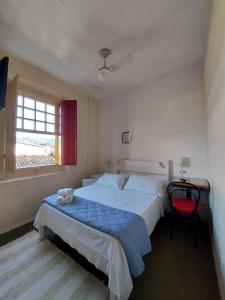 - une chambre avec un grand lit et une chaise rouge dans l'établissement Pousada Casa Da Lapa, à Parati