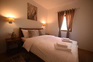 a bedroom with a white bed with two towels on it at VUKOVIC HOUSE-MOTICKI GAJ in Žabljak