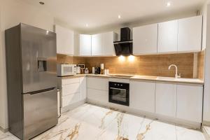 uma cozinha com armários brancos e um frigorífico de aço inoxidável em Dynasty Home Spa Appartement 100M Jacuzzi Terasse em Holtzheim