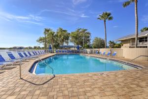 a large swimming pool with blue chairs and palm trees at Coastal-Zen Ruskin Retreat Less Than 1 Mi to Beach! in Ruskin