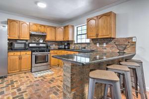 a kitchen with wooden cabinets and a island with bar stools at Ocean Springs Family Home Less Than 1 Mi to Beach in Ocean Springs