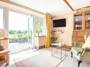 a living room with a tv and a sliding glass door at Bwythyn Y Wennol in Beddgelert