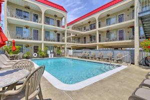 a pool in front of a hotel with chairs and a table at Quaint Wildwood Condo about Walk to Beach! in Wildwood