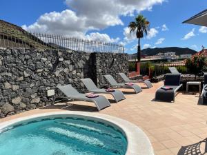 a swimming pool with lounge chairs and a stone wall at Villa Consuelo - Quiet Location Close to Resorts in Buzanada