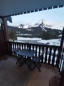 un banco en un balcón con vistas a una montaña nevada en Studio les fleury, en Mieussy