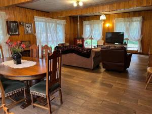 sala de estar con mesa y sofá en Hostal Casa de Campo Rukaleufu a orillas del Rio Huiscapi en Villarrica