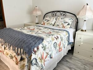 a bedroom with a bed with a floral bedspread and two lamps at Cute 1 bedroom Ohana 10 miles from Eugene in Creswell
