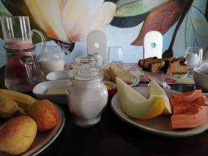 a table with plates of bread and fruit and milk at Dona Maragô Pousada in Maragogi