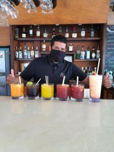a man wearing a mask behind a bar with drinks at Bella Vista Resort Belize in San Pedro