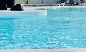 een groot zwembad van blauw water met stoelen erin bij Canaryislandshost l Las Olas in Costa Teguise