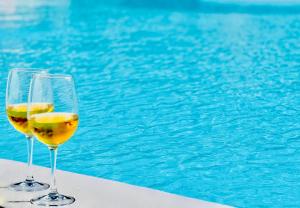 twee glazen wijn naast een zwembad bij Canaryislandshost l Las Olas in Costa Teguise