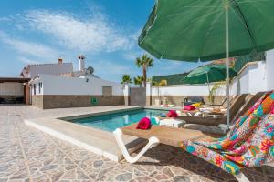 a swimming pool with a green umbrella and lounge chairs and a swimming pool at Villa La marina in Nerja