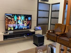 een woonkamer met een grote televisie en een bank bij 20PAX 4BR Villa with Kids Swimming Pool, KTV, Pool Table n BBQ near SPICE Arena Penang in Bayan Lepas