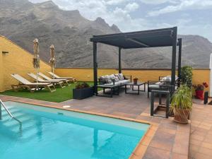 een patio met een zwembad met stoelen en een luifel bij Los Veroles in Agaete