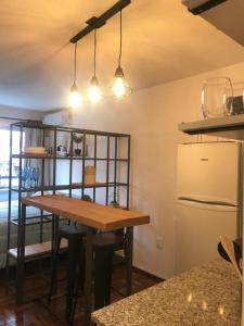 Il comprend une cuisine équipée d'une table en bois et d'un réfrigérateur. dans l'établissement Comodo monoambiente bien ubicado en Cordon, à Montevideo