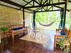 um alpendre com uma rede de descanso, uma mesa e cadeiras em Bahandi Beach Lodge em Mambajao