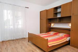 a bedroom with a bed and wooden cabinets at Apartment Supetarska Draga - Gornja 2016c in Supetarska Draga