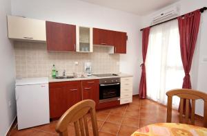 a kitchen with brown cabinets and a white refrigerator at Apartment Supetarska Draga - Gornja 2016c in Supetarska Draga