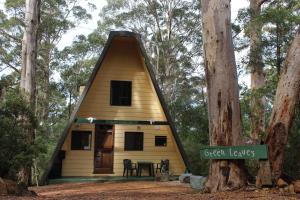 ein winziges Haus mit dreieckigem Dach im Wald in der Unterkunft Green Leaves Cabin in Denmark