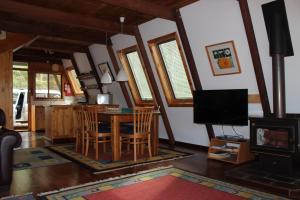 a living room with a table and chairs and a television at Green Leaves Cabin in Denmark