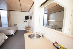 ein Bad mit einem Waschbecken, einem Bett und einem Spiegel in der Unterkunft Corio Bay Motel in Corio