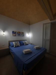 1 dormitorio con 1 cama azul y 2 toallas en TURISMO EGADI - CHARME en Favignana