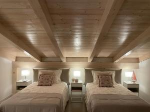 two beds in a room with wooden ceilings and two lamps at Villa Fiorentino in Rossano