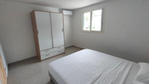 a white bedroom with a bed and a window at Les Eaux Turquoise in Terre-de-Haut