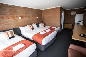 a hotel room with two beds and a brick wall at Moama Motel in Moama