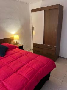 1 dormitorio con 1 cama grande de color rojo y vestidor en Apart Del Este 1 en Paysandú