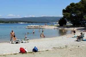 a group of people on a beach in the water at Apartments and rooms with parking space Krk - 3231 in Vrh