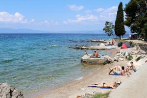 un grupo de personas yaciendo en una playa cerca del agua en Apartment Njivice 5320b en Njivice