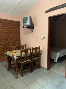 Habitación con mesa, sillas y TV en la pared. en Los Horneros, Cabañas en San Marcos Sierras