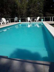 una gran piscina azul con sillas y sillas en Los Horneros, Cabañas en San Marcos Sierras