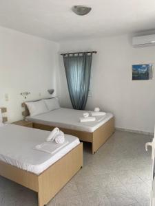 two beds in a hotel room with towels on them at VILLA NOULI in Sarakiniko