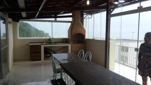 a woman standing in a kitchen with a table and a fireplace at Cobertura vista mar in Maricá