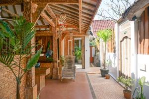 a porch of a house with a chair and plants at Jawa House Private Villas in Gili Trawangan