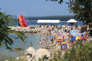 a bunch of people on a beach in the water at Double Room Punat 5363c in Punat