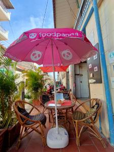 a table with a pink umbrella on a patio at Ganesha Hostel in Battambang