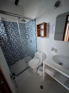 y baño con ducha, aseo y lavamanos. en Hotel El Embrujo en Villa de Leyva