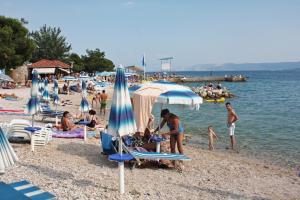 a crowd of people on a beach with umbrellas at Apartments by the sea Dramalj, Crikvenica - 5596 in Dramalj