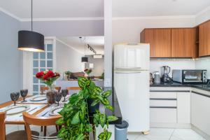 a kitchen with a table and a white refrigerator at Apartamento Moderno com Terraço à 4Km do Consulado USA in Porto Alegre