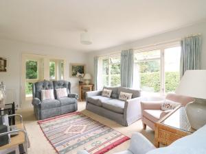 a living room with a couch and chairs and windows at Woodlands Cottage in Dorchester